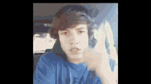 a young boy in a blue shirt is giving the middle finger while sitting in a car