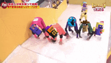 a group of people are crawling on the ground in front of a yellow wall with chinese writing