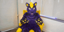 a purple and yellow furry animal is sitting in a yellow chair .