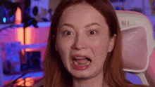 a woman is making a funny face while sitting in a gaming chair .
