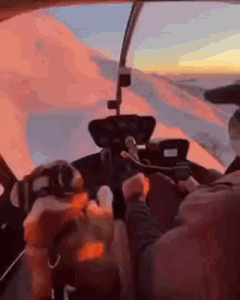 a man is sitting in the cockpit of a helicopter and holding a microphone .