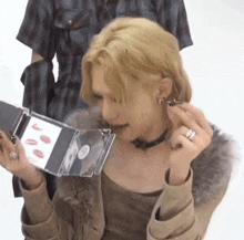 a woman with blonde hair is holding a cd case with lipstick on it