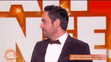 a man in a suit and bow tie stands in front of a large letter n