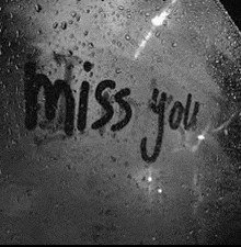 the words `` miss you '' are written on a wet window .