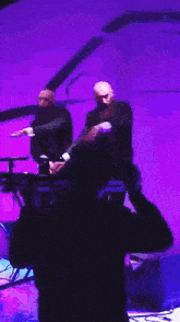 a couple of men are standing next to each other on a stage playing a keyboard .
