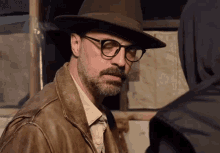 a man with a beard wearing a hat and glasses .