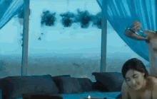 a man and a woman are laying on a bed with a blue curtain .