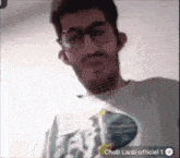 a man with glasses and a beard is wearing a shirt that says cheb larbi officiel 1 .