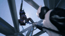 a man in a mask is hanging from a metal beam
