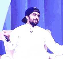 a man with a beard wearing a black hat with the word reebok on it
