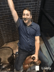 a man in a blue shirt is kneeling on a saddle with his arms in the air