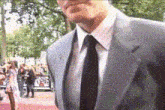 a man in a suit and tie is walking on a red carpet