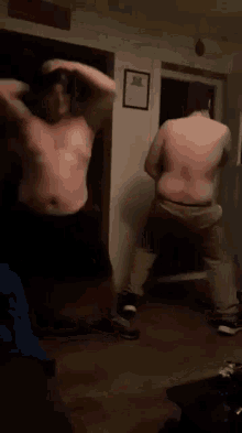 two fat men are dancing in a dark room .