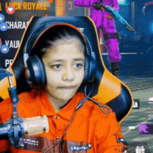 a little girl wearing headphones and a microphone is sitting in a chair .