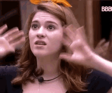 a woman wearing a headband and a microphone is making a funny face .