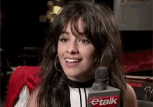 a woman is smiling while holding a microphone with the word talk on it .