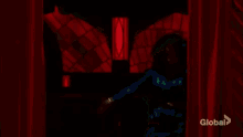 a woman in a green dress is standing in front of a red curtain in a room .