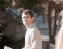 a man in a tan sweater is walking down a sidewalk