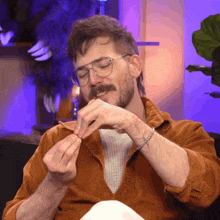 a man with glasses and a beard is sitting on a couch eating something