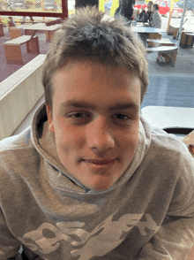 a young man wearing a grey sweatshirt that says ' osaka ' on the front