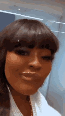 a close up of a woman 's face with a fringe and a white robe .