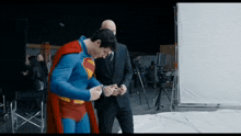 a man in a superman costume is standing next to another man