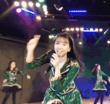 a girl in a green sequined dress is dancing on stage