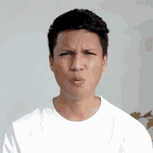 a man in a white t-shirt is making a funny face .