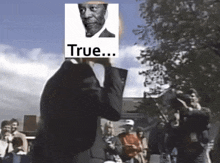 a man in a suit stands in front of a crowd with a picture of a man on his face and the words true on it