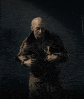 a man without a shirt is standing in the dark with a sword on his shoulder