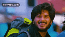 a man with a beard is smiling with a backpack on his back