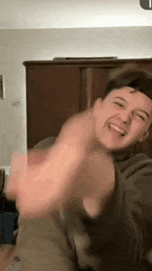 a young man in a hat is making a funny face while dancing in a room .