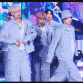 a group of young men are standing on a stage wearing blue jackets and hats