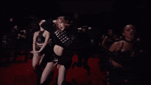 a group of women are dancing on a red carpet in front of a crowd
