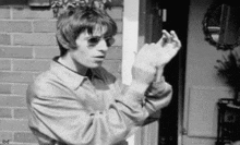 a man wearing sunglasses and a jacket is standing in front of a door .