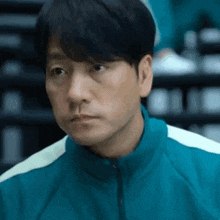 a close up of a man wearing a blue jacket and looking at the camera .