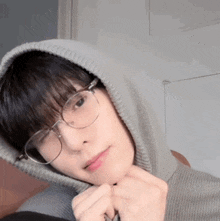 a young man wearing glasses and a hoodie looks at the camera .