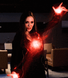 a woman with red lights coming out of her hands and a couch in the background