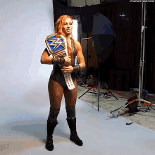 a woman in a wrestling outfit is holding a wrestling championship belt in a studio .