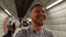 a man is smiling in a subway with a sign that says " hear the food "