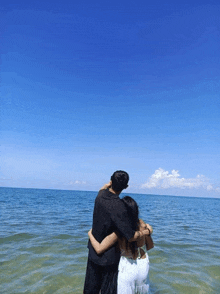 a man and a woman are standing in the ocean looking at the ocean .