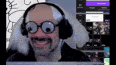 a man wearing glasses and headphones is smiling in front of a computer screen