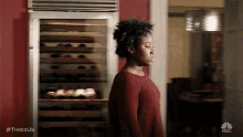 a woman is standing in front of a wine fridge in a kitchen .