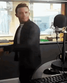 a man stands in front of a microphone in a radio studio