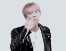 a man in a leather jacket is making a funny face with his hands .