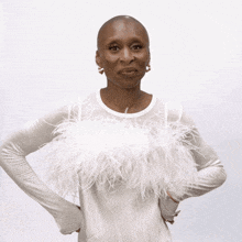 a woman wearing a white top with feathers on it is laughing