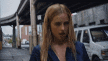 a blonde woman in a blue shirt is walking down a street