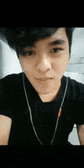 a close up of a person wearing a black shirt and earbuds