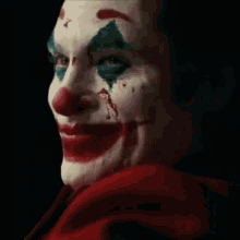 a close up of the joker 's face with blood coming out of his nose .