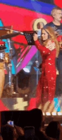 a woman in a red jumpsuit is holding a microphone on a stage